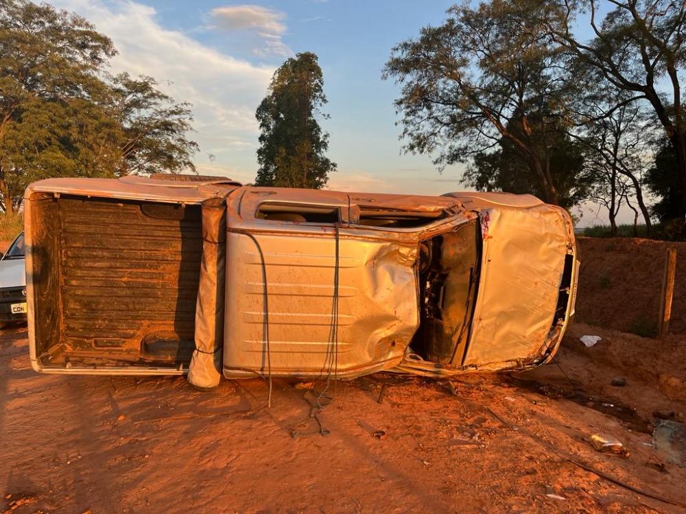 Caminhonete capota com três pessoas em estrada rural